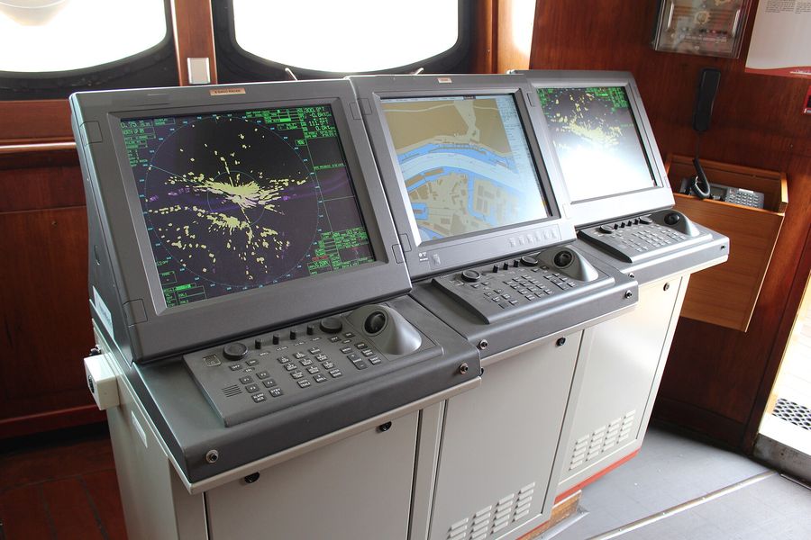 Consoles de radar e ECDIS no passadiço de um navio